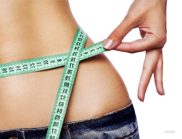 Hand measuring waist with tape measure