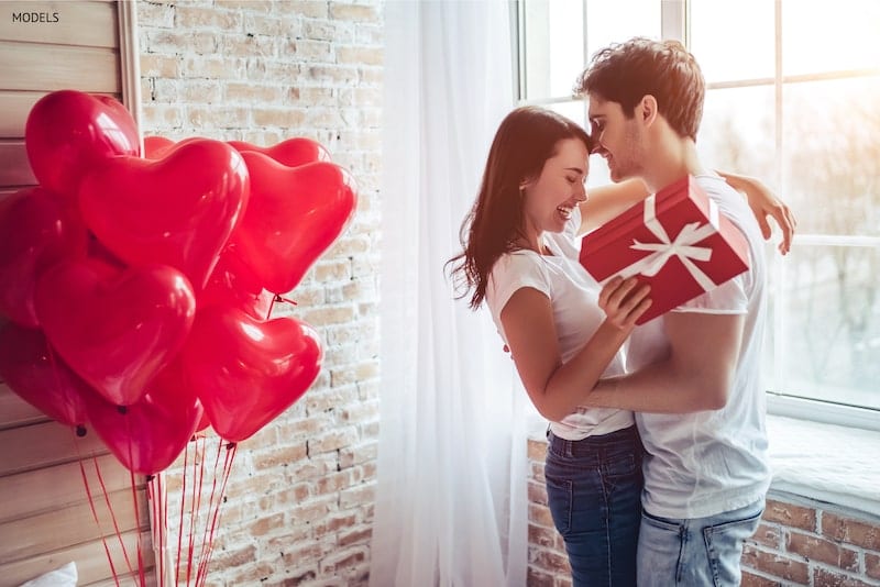 Couple on Valentine's Day hugging after giving a gift.