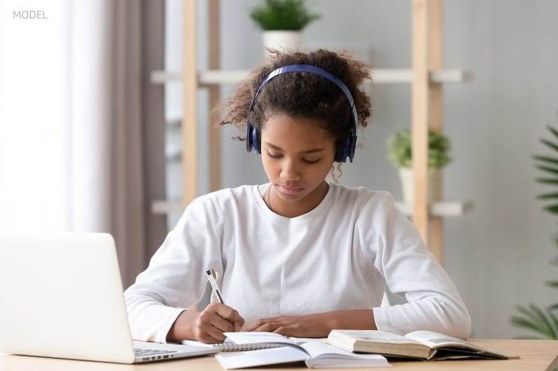 Young teenager doing homework in front of a computer.