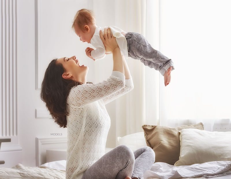Attractive mom playing with her son by tossing him into the air and catching him