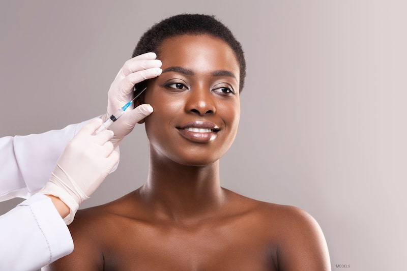 Young woman getting BOTOC® Cosmetic injection in temple.